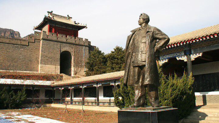 A statue in front of a large gate at the Huangyaguan Great Wall fort