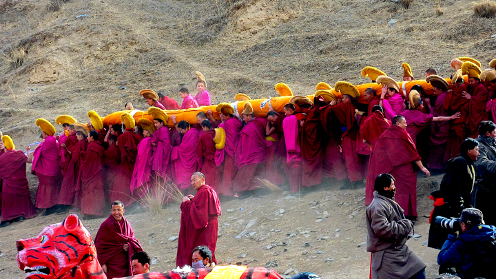 A rolled thangka is carried towards the hills