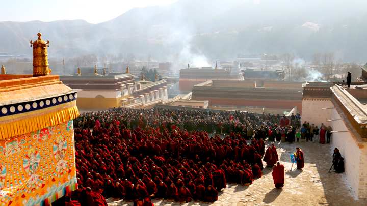 A gathering of monks, in front of a hall in the monastery