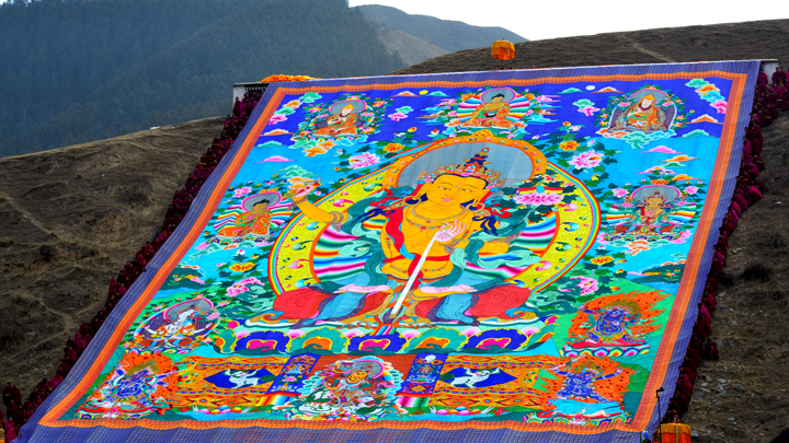 The thangka is displayed on the hillside