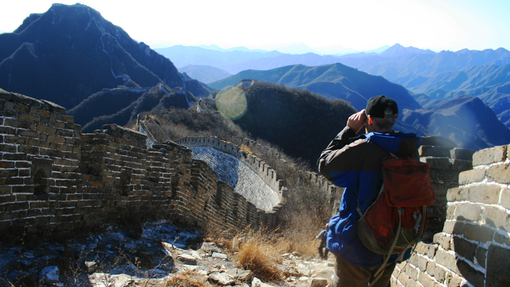 A hiker using binoculars to get a closer look at a stretch of the Jiankou Great Wall