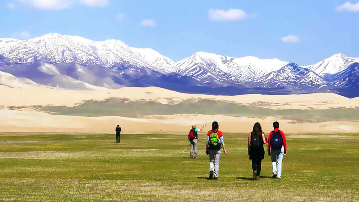 Hiking in grassy meadows near Qinghai Lake, with the Qilian Mountains seen in the distance